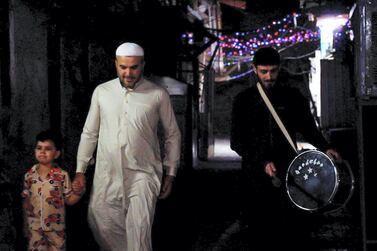 A drummer walks down the street in Baghdad during Ramadan. Haider Husseini