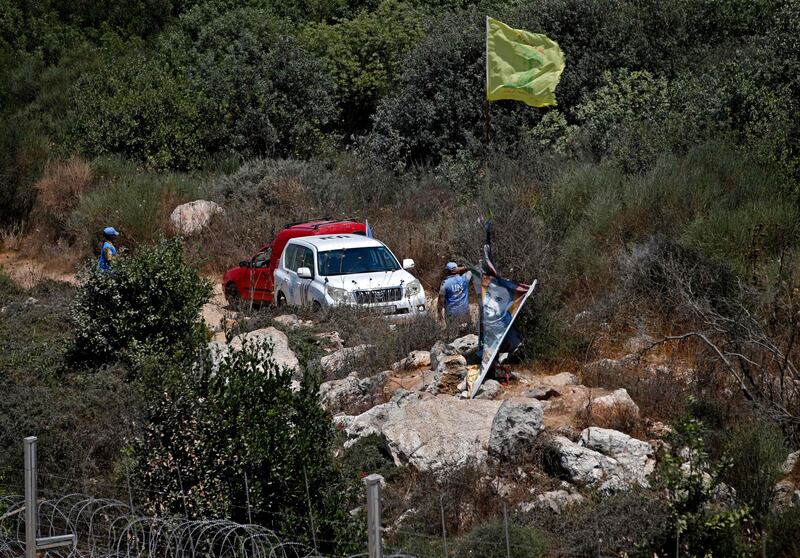 UN peacekeepers stand next to a Hezbollah flag raised on the Lebanese side of the border with Israel, near the northern Israeli settlement of Shtula, on Tuesday. AFP