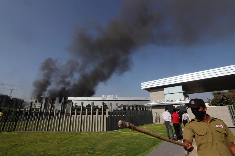 A security man tries to keep people away as smoke rises from a fire at Serum Institute of India in Pune. AP Photo