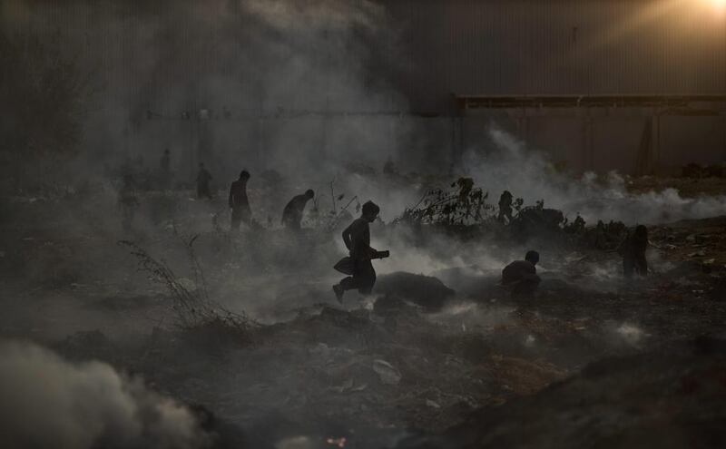 Pakistani children pick through a burning field that was used by fruit and vegetable sellers to store their wooden boxes, on the outskirts of Islamabad, Pakistan on November, 4, 2013. According to the crowds at the site, the Capital Development Authority burned the field because it was used by the sellers to store their wooden boxes illegally.  Muhammed Muheisen / AP Photo