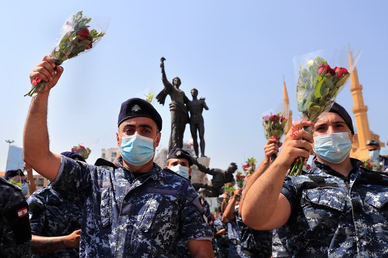 Police hold flowers to mark the anniversary of the Beirut port explosion.