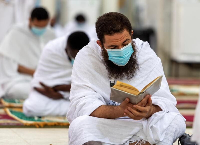 A Muslim pilgrim wearing a protective mask, reads the Quran.  REUTERS