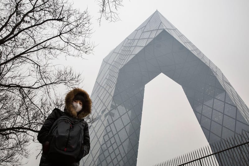 BEIJING, CHINA - DECEMBER 08:  A Chinese woman wears a mask to protect against pollution as she passes the CCTV building in heavy smog on December 8, 2015 in Beijing, China. The Beijing government issued a "red alert" for the first time since new standards were introduced earlier this year as the city and many parts of northern China were shrouded in heavy pollution. Levels of PM 2.5, considered the most hazardous, crossed 400 units in Beijing, lower than last week, but still nearly 20 times the acceptable standard set by the World Health Organization. The governments of more than 190 countries are meeting in Paris to set targets on reducing carbon emissions in an attempt to forge a new global agreement on climate change.  (Photo by Kevin Frayer/Getty Images)