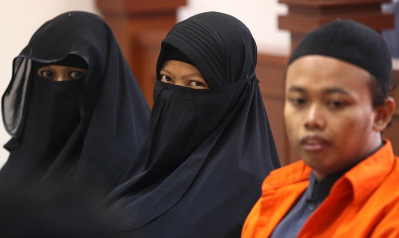 Indonesian militant Dian Yulia Novi, center, is flanked by her husband Nur Solihin, right, and her recruiter Tutin as they sit on the defendant's bench during their trial hearing at East Jakarta District Court in Jakarta, Indonesia, Wednesday, Aug. 23, 2017. Prosecutors demanded that Novi, a would-be suicide bomber, should spend 10 years in prison for plotting an attack in Indonesia's capital.  Police say Novi planned to detonate a 3-kilogram (6.6-pound) bomb that would have exploded as crowds of people gathered to watch the ceremony, a popular family attraction in Jakarta.  Prosecutors also demanded five and 15 years jail term for Tutin and Solihin respectively. (AP Photo/Achmad Ibrahim)