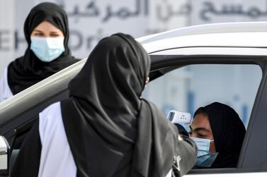 A health worker takes a body temperature reading from a driver inside a vehicle at a drive-through Covid-19 testing centre in Dubai. AFP 