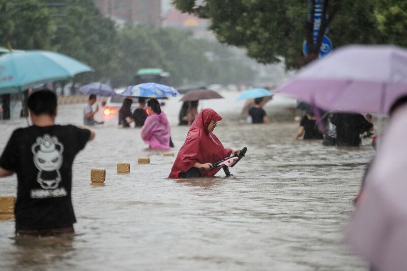 People make their way along a flooded street in Zhengzhou.