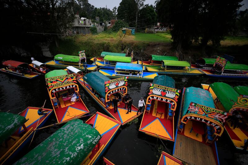 Boats carrying passengers come in to dock amidst parked "trajineras," the colorful passenger boats typically rented by tourists and families in Xochimilco, Mexico City.  AP