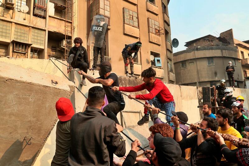 Anti-government protesters try to pull down concrete walls during clashes with security forces in Baghdad. AP Photo