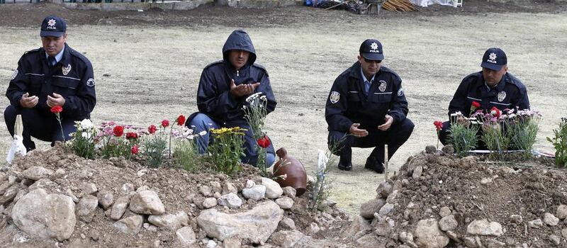 Policemen pray next to graves of the miners. Tolga Bozoglu / EPA / May 17, 2014 