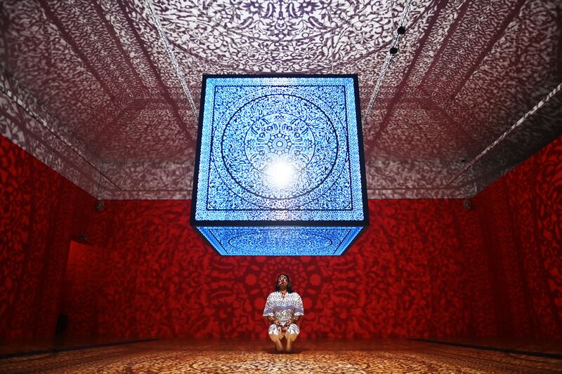 A gallery worker poses with the work All the Flowers are for Me by Pakistani-American artist Anila Quayyum Agha at Kew Gardens in London, on March 30. EPA