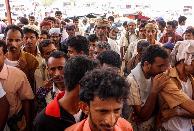 Yemeni civilians queue up to receives food aid for displaced people who fled battles in the Red Sea province of Hodeida and are now living in camps in the northern district of Abs, under control by the Iranian-backed Huthi rebels in Hajjah province, on June 24, 2018.  / AFP / ESSA AHMED
