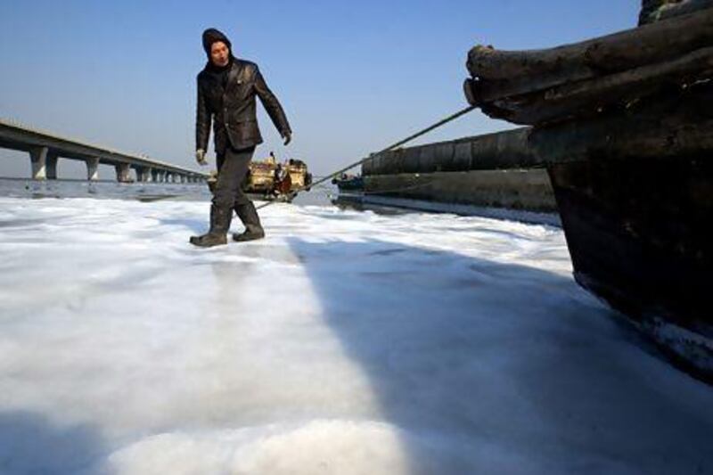 A fisherman walks on the sea ice as the fishing boats are trapped by sea ice at Jiaozhou Bay in rural Qingdao city, eastern China's Shandong province. Wu Hong / EPA