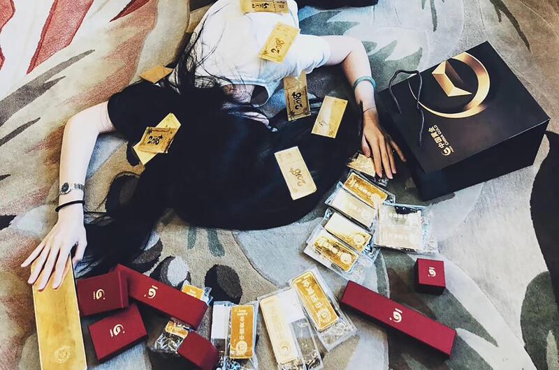 This handout picture released to AFP courtesy of Wei Shengju on October 25, 2018 and taken on October 10 shows Wei Shengju lying on the floor, posing for a picture with gold bars in Beijing. - Chinese social media users have seized on a viral meme in which people are pictured literally roll in their own wealth, spawning a range of cheeky counter-posts poking fun at the country's nouveau riche. (Photo by Handout / COURTESY OF WEI SHENGJU / AFP) / -----EDITORS NOTE --- RESTRICTED TO EDITORIAL USE - MANDATORY CREDIT "AFP PHOTO / Courtesy of WEI SHENGJU" - NO MARKETING - NO ADVERTISING CAMPAIGNS - DISTRIBUTED AS A SERVICE TO CLIENTS - NO ARCHIVES