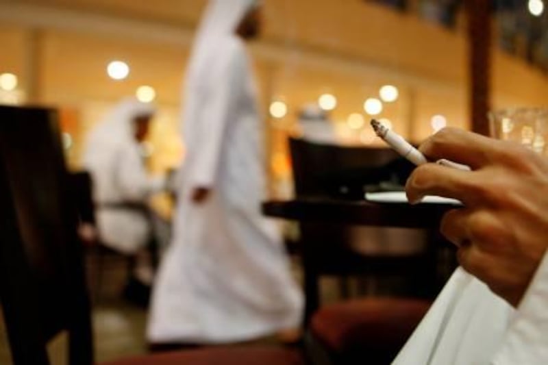 ABU DHABI, UNITED ARAB EMIRATES - January 12, 2009: A man smokes a cigarette at a cafe in Marina Mall, Abu Dhabi. The United Arab Emirates government is in the process of implementing a smoking ban. ( Ryan Carter / The National ) *** Local Caption ***  RC008-Smoking-20100112.jpg