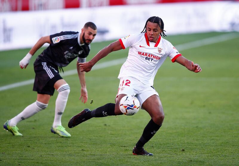 Jules Kounde of Sevilla FC takes a shot under pressure from Karim Benzema. Getty