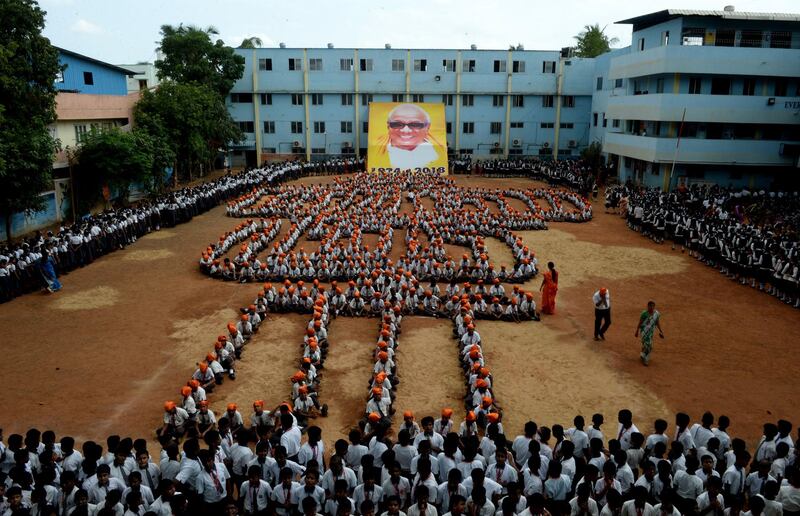 Indian school students gather to pay homage to a portrait of the deceased Muthuvel Karunanidhi, president of the Dravida Munnetra Kazhagam party, at a school in Chennai on August 9, 2018. - Thousands mourn in southern India on August 7 after the death of revered 94-year-old political leader Muthuvel Karunanidhi. (Photo by ARUN SANKAR / AFP)