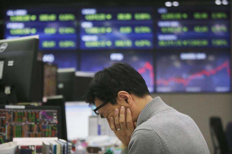 In this Thursday, March 12, 2020, photo, a currency trader covers his face at the foreign exchange dealing room of the KEB Hana Bank headquarters in Seoul, South Korea. Asian stock markets and U.S. futures fell Monday, March 16, 2020, after the Federal Reserve slashed its key interest rate to shore up economic growth in the face of mounting global anti-virus controls that are shutting down business and travel. (AP Photo/Ahn Young-joon)