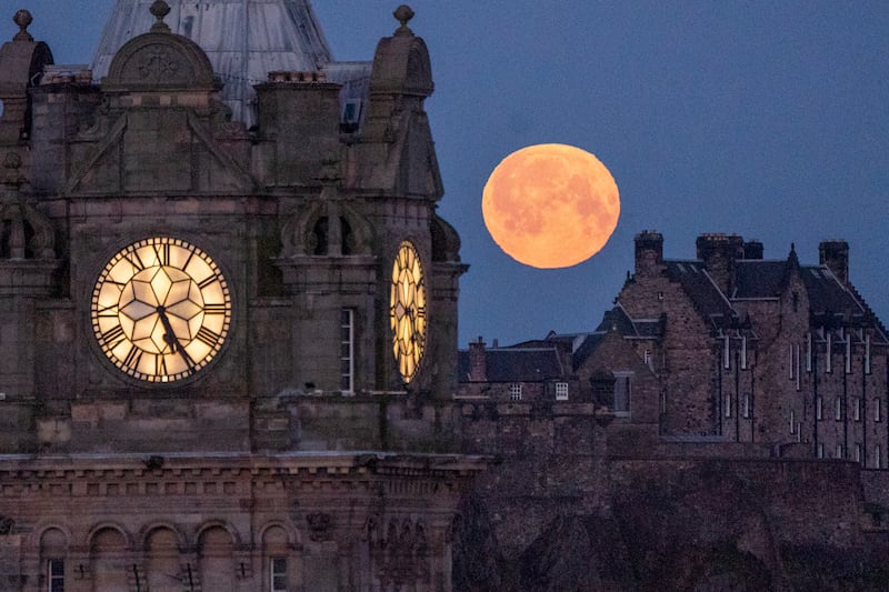 The full moon, known as the 'Pink Moon' during April, sets behind the Balmoral Clock and Edinburgh Castle. PA