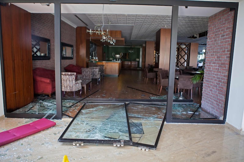 A picture taken on September 12, 2019 shows shattered glass doors at the Acapulco hotel in Kyrenia (Girne) in the self-proclaimed Turkish Republic of Northern Cyprus (TRNC) north of the divided Cypriot capital Nicosia, after the building was damaged when a military depot exploded nearby. Multiple explosions at a Turkish military base in northern Cyprus damaged a hotel in a neighbouring holiday resort early Thursday, prompting the evacuation of terrified tourists, officials said. Fire broke out in the arms depot at the base in Catalkoy, west of the town of Kyrenia, without causing any casualties, police said. / AFP / Birol BEBEK
