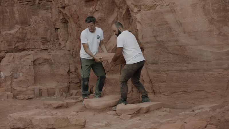 Archaeologists carrying a statute found during excavation, dating back some 2,000 years