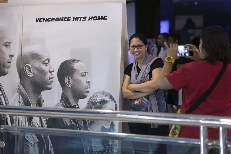 People pose for pictures with a Furious 7 poster before they enter the cinema to view the first showing of the movie in Abu Dhabi, at Vox Cinema in Marina Mall. Silvia Razgova / The National