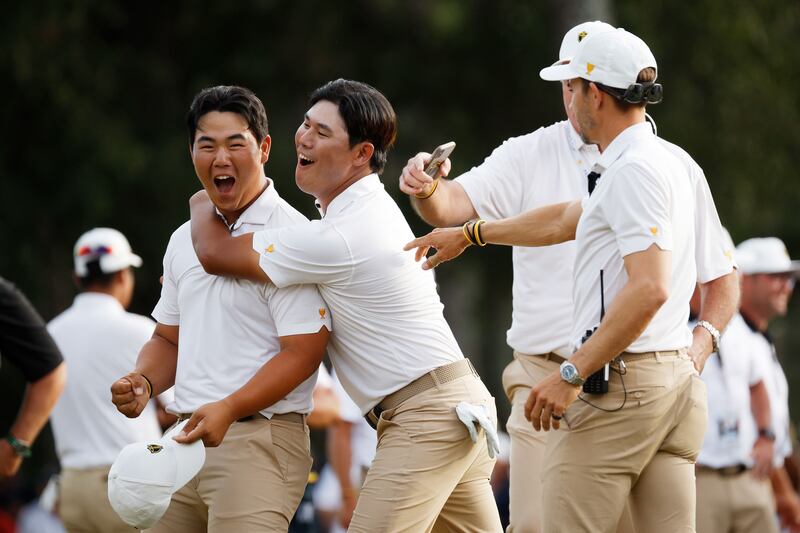 Tom Kim, left, celebrates with International team teammates after his hole-winning putt to beat Patrick Cantlay and Xander Schauffele on Day Three of the 2022 Presidents Cup. Getty