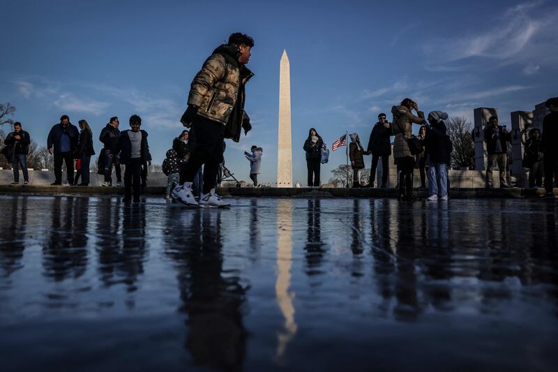 People play on the frozen Reflecting Pool on the National Mall near the Washington Monument, in Washington, DC.  AFP