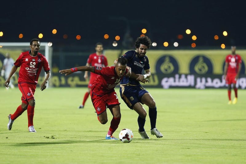 Michael N'dri, centre, of Al Shaab fights his way past Saleh Saidi of Dubai during their Arabian Gulf League match in Dubai on April 27, 2014. Antonie Robertson / The National