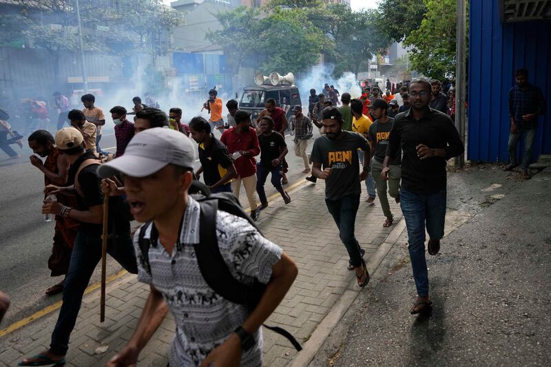 Anti-government protesters flee as police fire teargas. AP