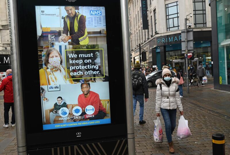 A pedestrian wearing a mask because of the novel coronavirus pandemic walks in central Manchester, north west England on November 4, 2020, as the country prepares for a second Covid-19 lockdown in an effort to combat soaring infections. England heads into a second national lockdown on November 5. / AFP / Oli SCARFF
