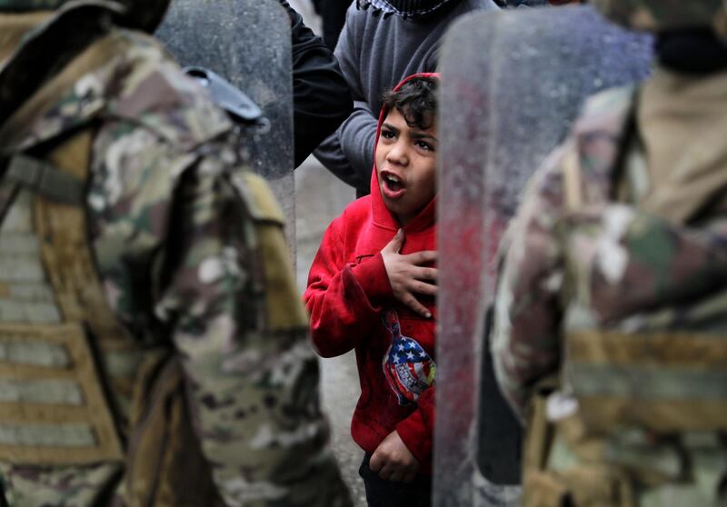 A boy gestures as protesters confront security forces while going around the homes of deputies and government officials in the northern port city of Tripoli. AFP