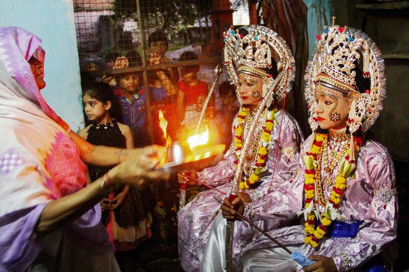 A Hindu performs an 'Arti' Puja, a prayer ritual to worship a deity, as artists dressed as Hindu god Rama and his companion Laxman sit inside a temple before a religious procession during a Dussehra festival in Allahabad. AFP