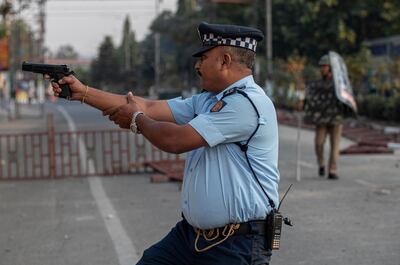 An Indian police officer aims his gun before firing at stone throwing protesters in Gauhati, India, Thursday, Dec. 12, 2019. No one was hurt in the firing. Police arrested dozens of people and enforced a curfew Thursday in several districts in Indiaâ€™s northeastern Assam state where thousands protested legislation that would grant citizenship to non-Muslims who migrated from neighboring countries. (AP Photo/Anupam Nath)