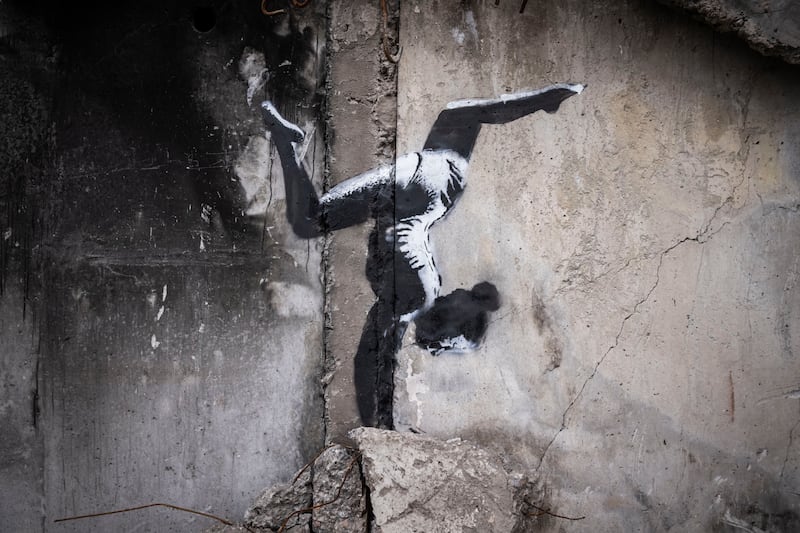 A Banksy artwork of a woman in a leotard doing a handstand is seen on the wall of a destroyed building in Borodyanka. Getty.