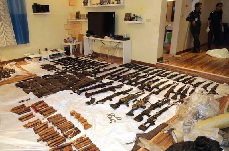Kuwaiti police stand next to the weapons seized on Thursday. AFP PHOTO / HO / KUNA

