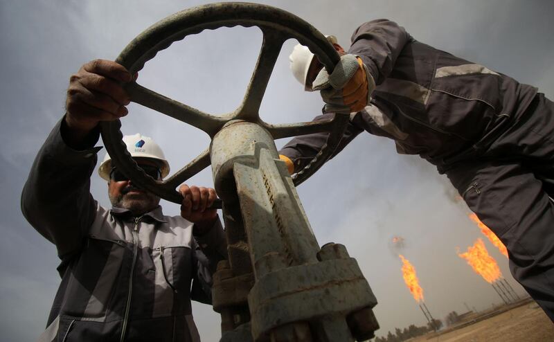 Iraqi oil technicians turn a valve at a gas installation as flames resulting from the burning of excess hydrocarbons rise in the background at the Nahr Bin Omar natural gas field, north of the southern Iraqi port of Basra on January 22, 2018.
Iraq will is expected to sign a memorandum of understanding with US energy company Orion on January 22 to tap gas at the oil field in the south of the country, the petroleum ministry said. 
The Nahr Bin Omar field, situated in the hydrocarbon-rich Basra province, is currently producing 40,000 barrels of oil a day, but only a small part of the gas from the field is being exploited.  / AFP PHOTO / HAIDAR MOHAMMED ALI