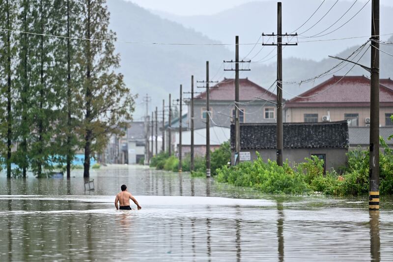 A man walks down a flooded area in Yuyao near the city of Ningbo in eastern China's Zhejiang province after heavy rains brought by Typhoon In-Fa.