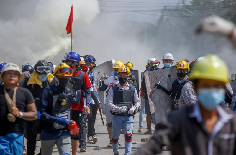 Anti-coup protesters retreat after discharging fire extinguishers towards a line of riot policemen in Yangon, Myanmar. AP