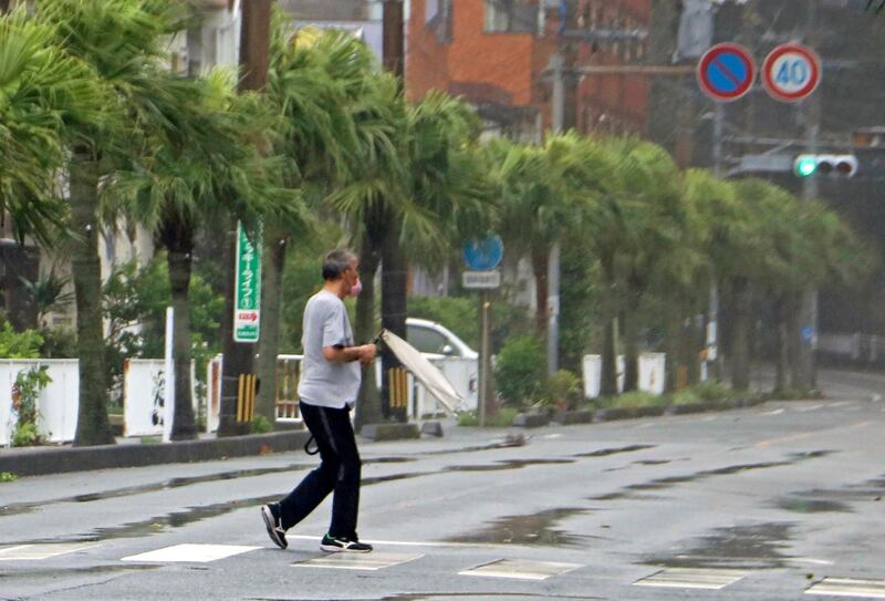 A man makes his way through strong wind with his umbrella broken by the wind in Amami city, Kagoshima prefecture, southwestern Japan.   AP