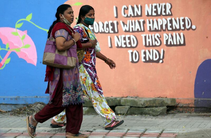 Women walk in front of a graffiti painted on a roadside wall in Bangalore, India. EPA