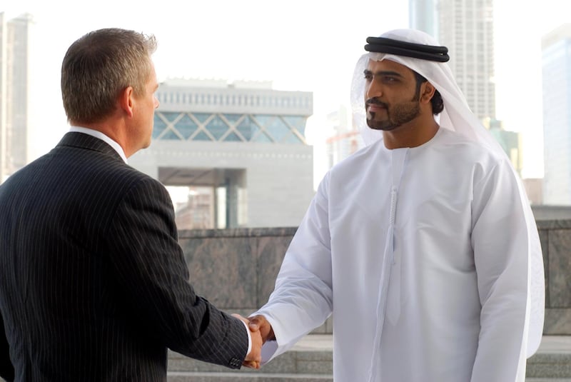 Arab man shaking hands with businessman in Dubai, UAE.