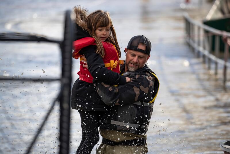 A volunteer carries a young girl to safety after she was stranded by rising water in Abbotsford.