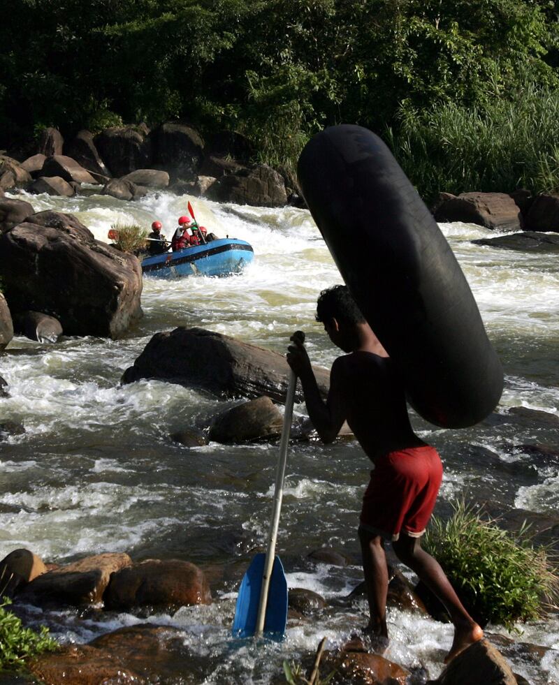 Tourists enjoy white water rafting as a Sri Lankan man carries a rubber tube on the banks of the Kelaniya river, the 2nd largest river in island, Kitulgala, Sri Lanka March 21, 2006. Each year, a different United Nations (UN) agency is selected to coordinate events surrounding World Water Day (WWD) around the world, and a different theme is chosen to reflect the many facts of freshwater resources. World Water Day, March 22, 2006, will be coordinated by United Nations Educational, scientific and Cultural Organization (UNESCO), under the theme "Water and Culture". REUTERS/Anuruddha Lokuhapuarachchi - RTR17H4Y
