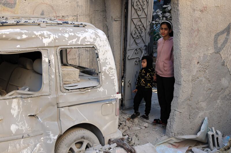 Children walk past a damaged car after an early morning Israeli strike in Rafah. AFP
