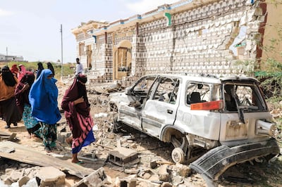 Women walk past a destroyed house and the wreckage of a car after an explosion set off by Al Shabab militants in Mogadishu, Somalia, in February. AFP