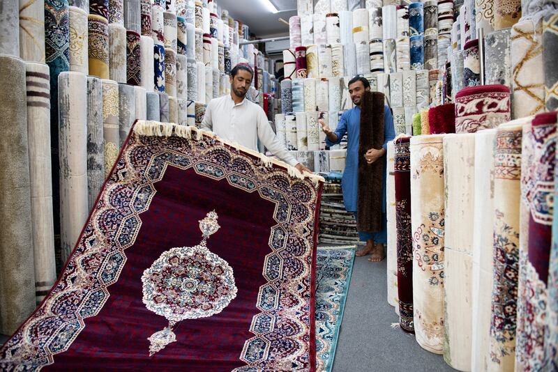 Carpet sellers prepare to welcome customers to their store.