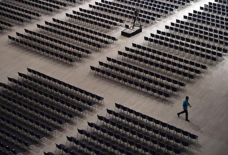 An employee walks between seats ahead of the Siemens company's annual shareholder's meeting in the Olympic hall in Munich, southern Germany, on January 30, 2019. German industrial giant Siemens on January 30, 2019 reported slumping profits in its first quarter, although order books were well filled ahead of a planned merger of its rail division with France's Alstom.  / AFP / Christof STACHE
