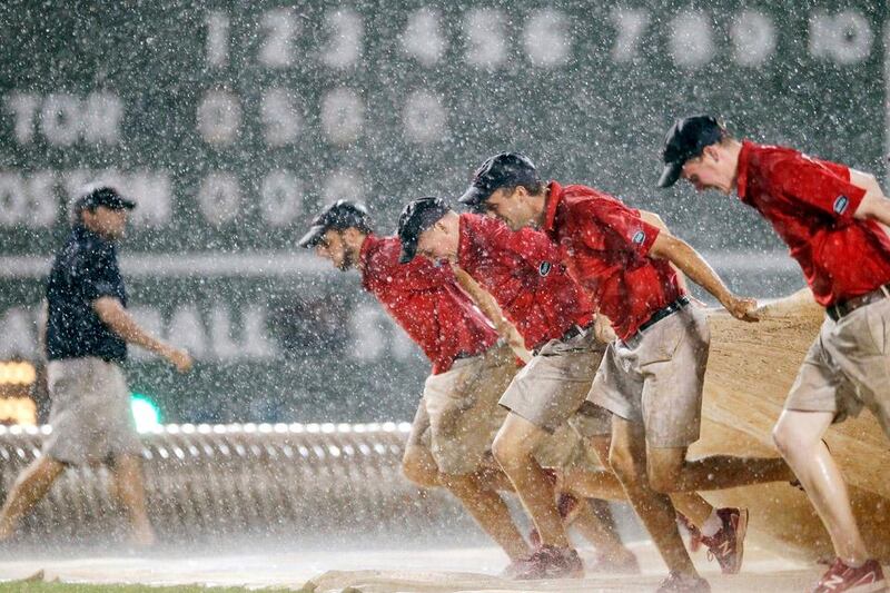 The Fenway Park grounds crew pulls out the tarp in heavy rain in the fourth inning of a baseball game between the Boston Red Sox and the Toronto Blue Jays in Boston, Saturday, Sept. 8, 2012. (AP Photo/Michael Dwyer)