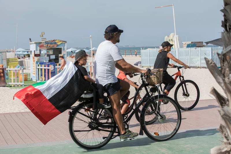 A flag-carrying family cycle along Kite Beach.  Ruel Pableo / The National