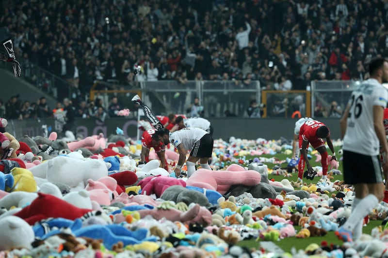 Players from Besiktas and Antalyaspor move toys to side of pitch after fans threw them down from stands. AFP